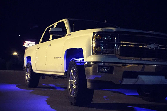 White truck with blue lights underneath in the night time