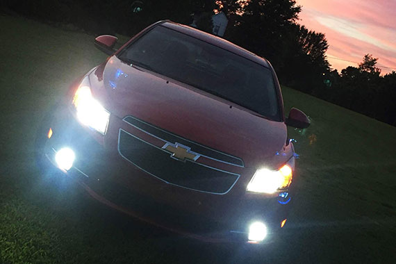 Red car showing cleaned headlights in the night time