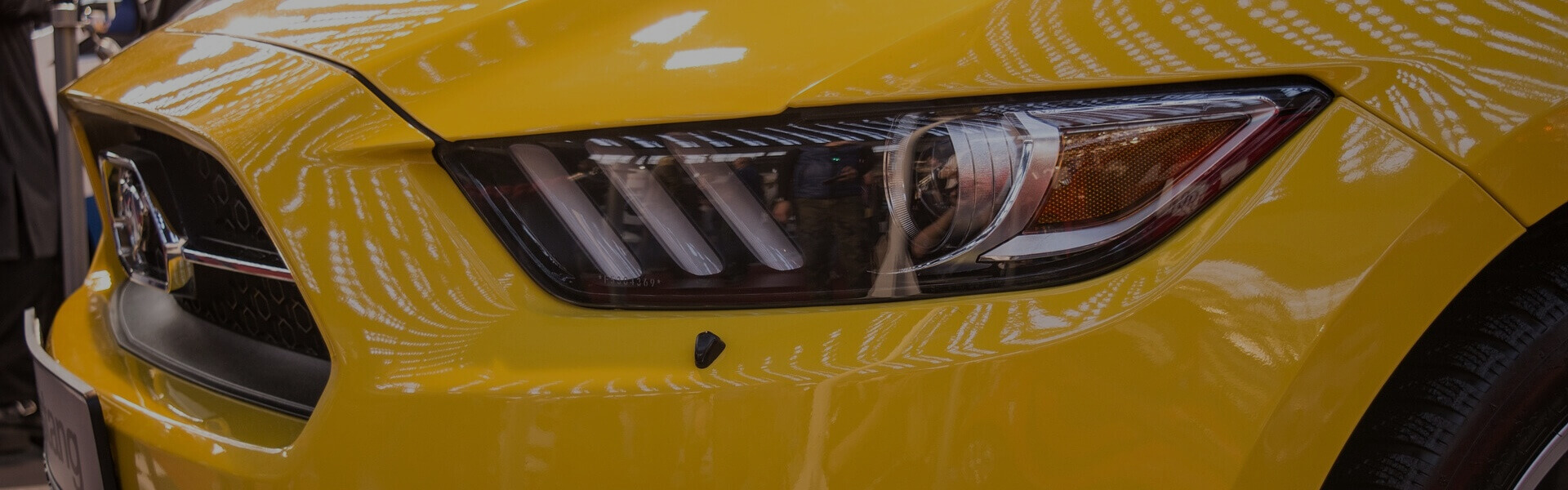 Close up image of the headlight of a yellow Mustang